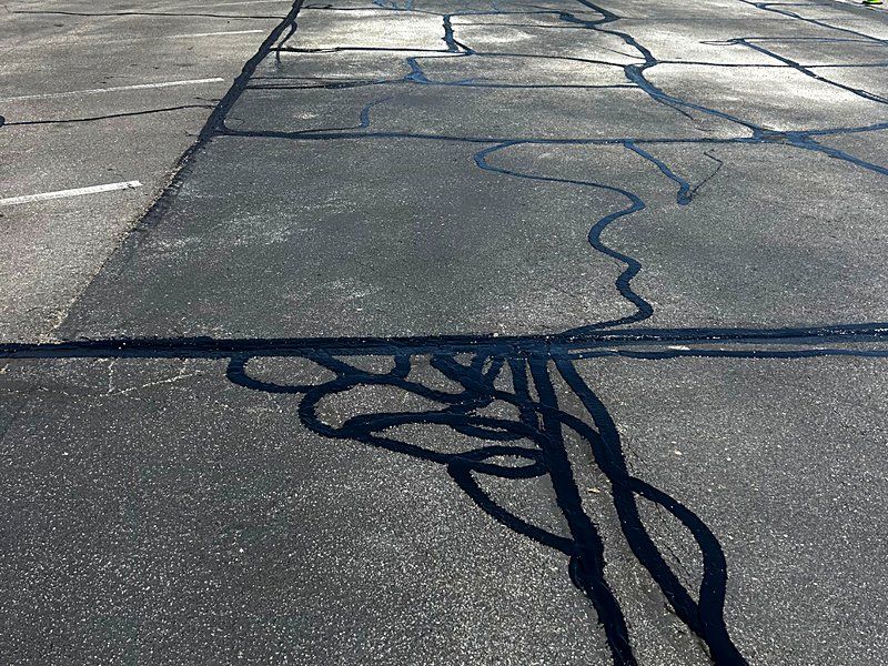 Hot rubberized sealant locked into cracks across a commercial lot