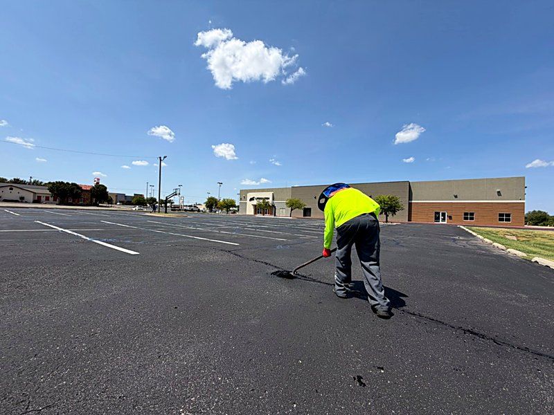 Technician finishing fresh pavement work on a commercial lot