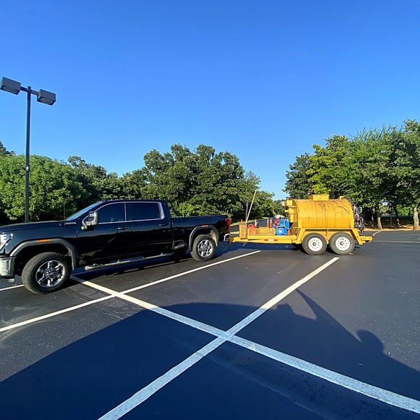 Heartland Pavement Services truck and sealcoating rig on a freshly striped commercial lot